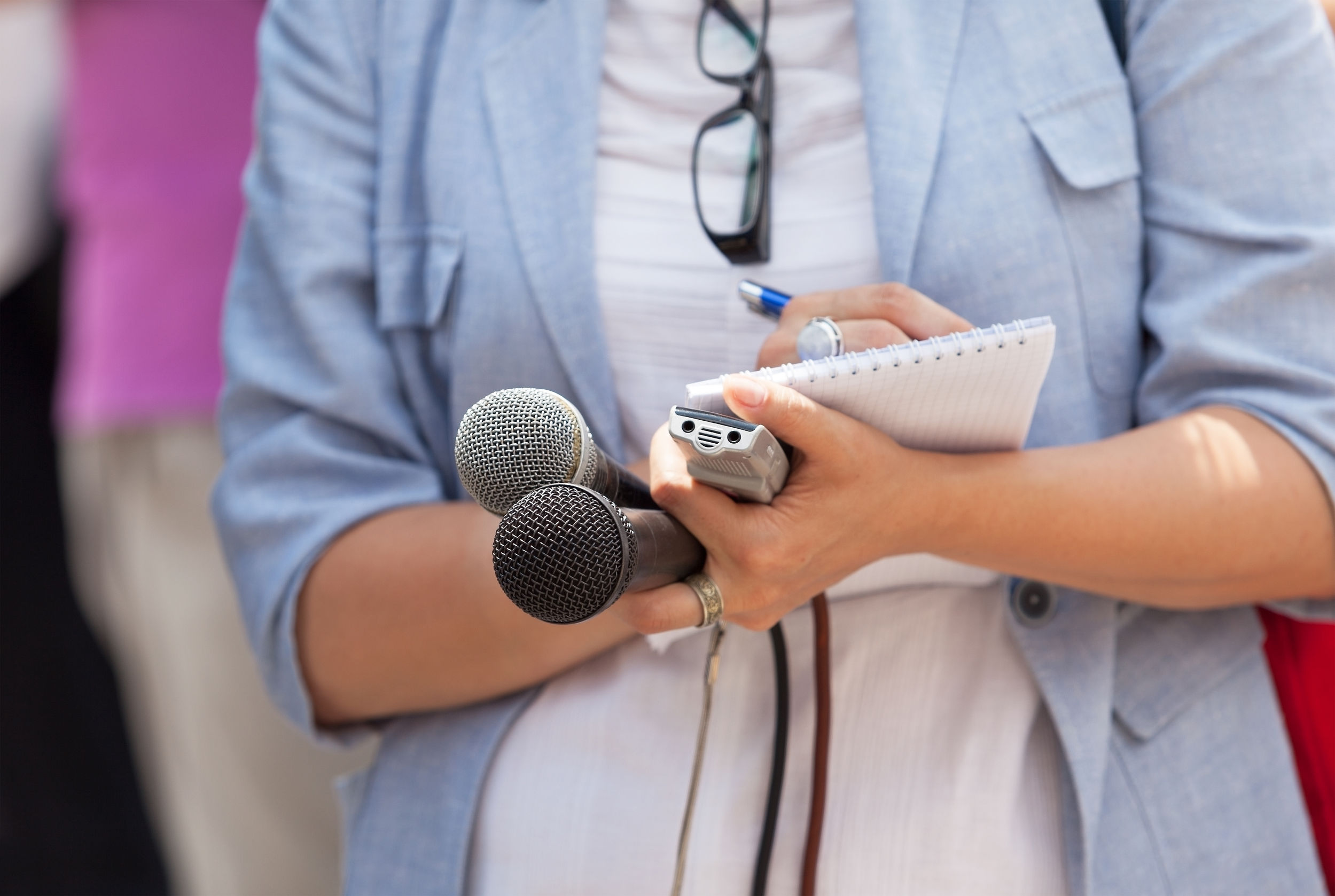 A reporter holding a notepad, recorder and microphone. (Journalists share best practices for pitching an exclusive)