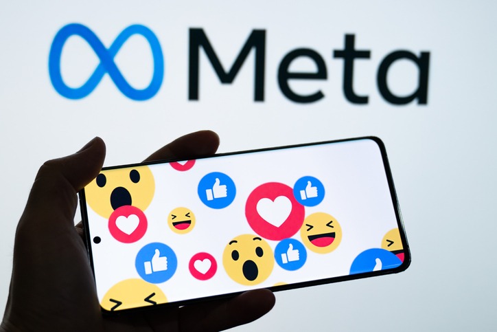 The Meta logo behind a of a person holding a cellphone full of emojis. (The Scoop: Meta shuts down disinformation tool ahead of U.S. election)