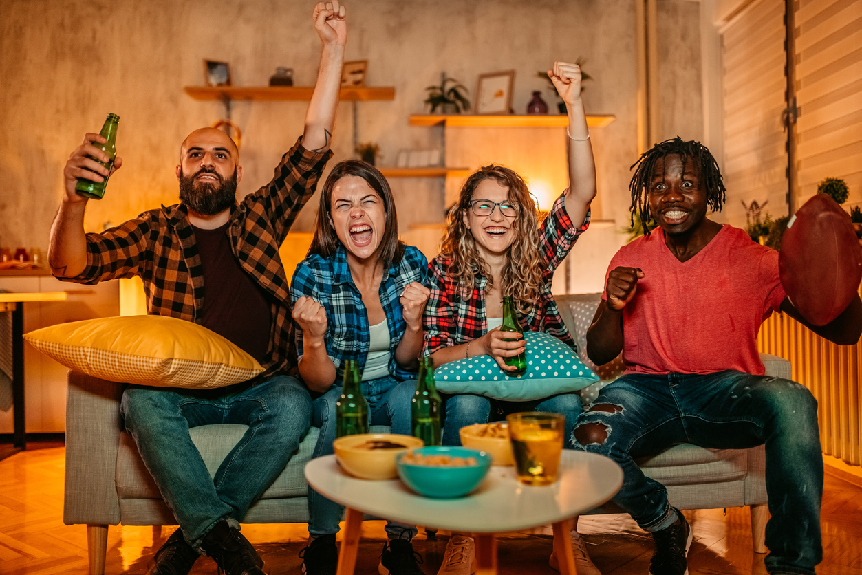 Young men and women with beer and popcorn cheering for winning team while watching American football game. Joe Burrow's sex appeal is growing among football fans with the encouragement of the NFL.