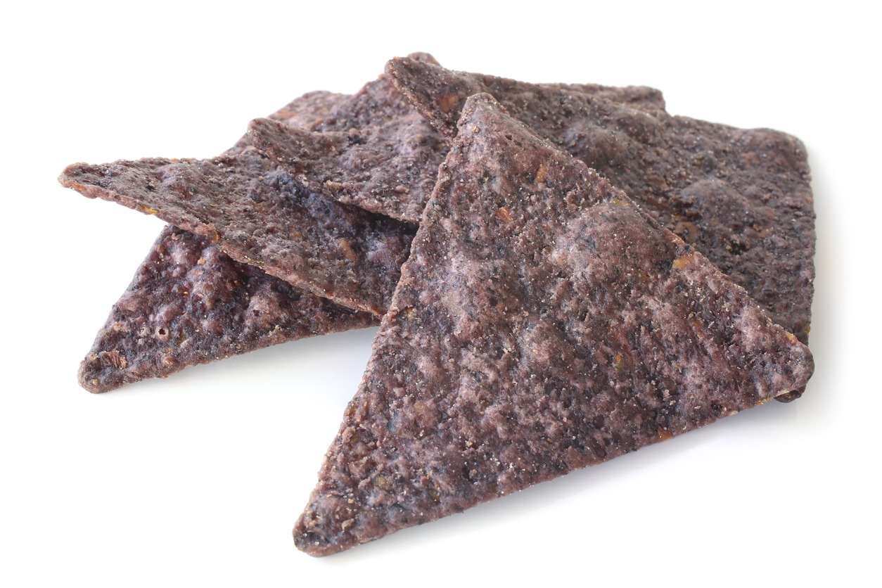 Blue corn tortilla chips on white background. It represents Paqui chips.