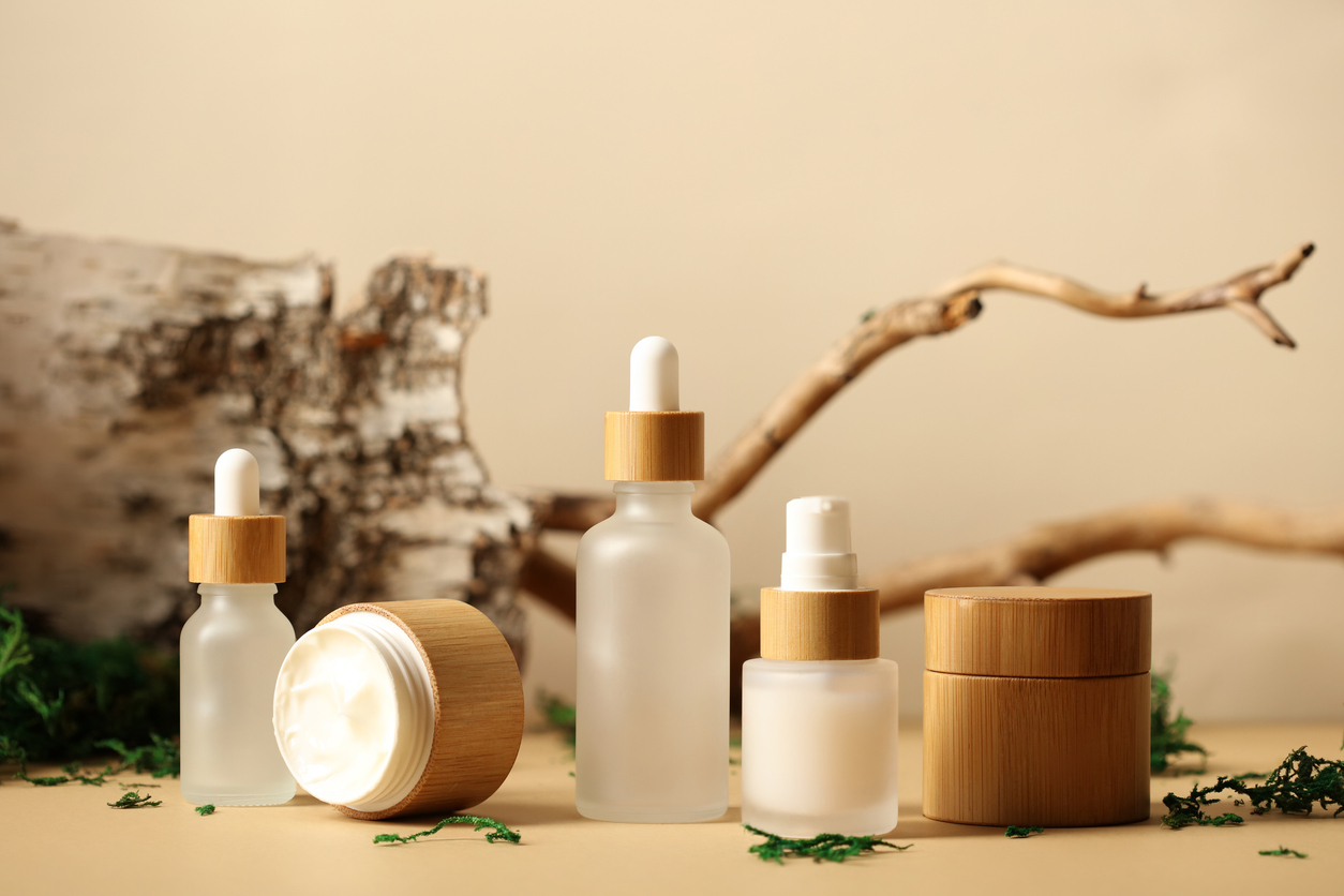 SPA natural organic cosmetics packaging design. Set of transparent glass bottles, moisturizer cream in wooden jars. Tree branch, birch bark and moss on background. Gwyneth Paltrow's Goop still sales well.