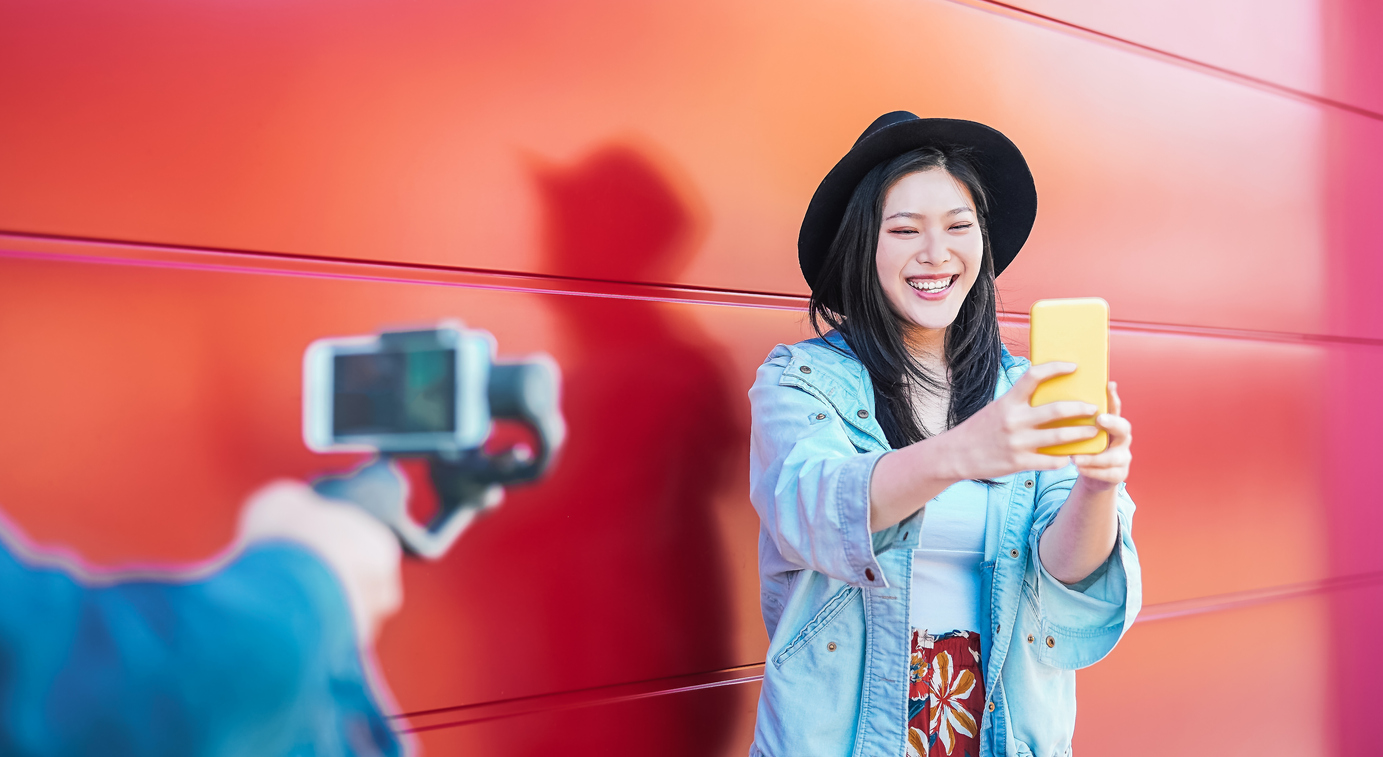 Asian fashion woman vlogging and using mobile smart phone outdoor - Happy Chinese trendy girl having fun making video with gimbal camera - Millennials people, Generation z and technology concept.