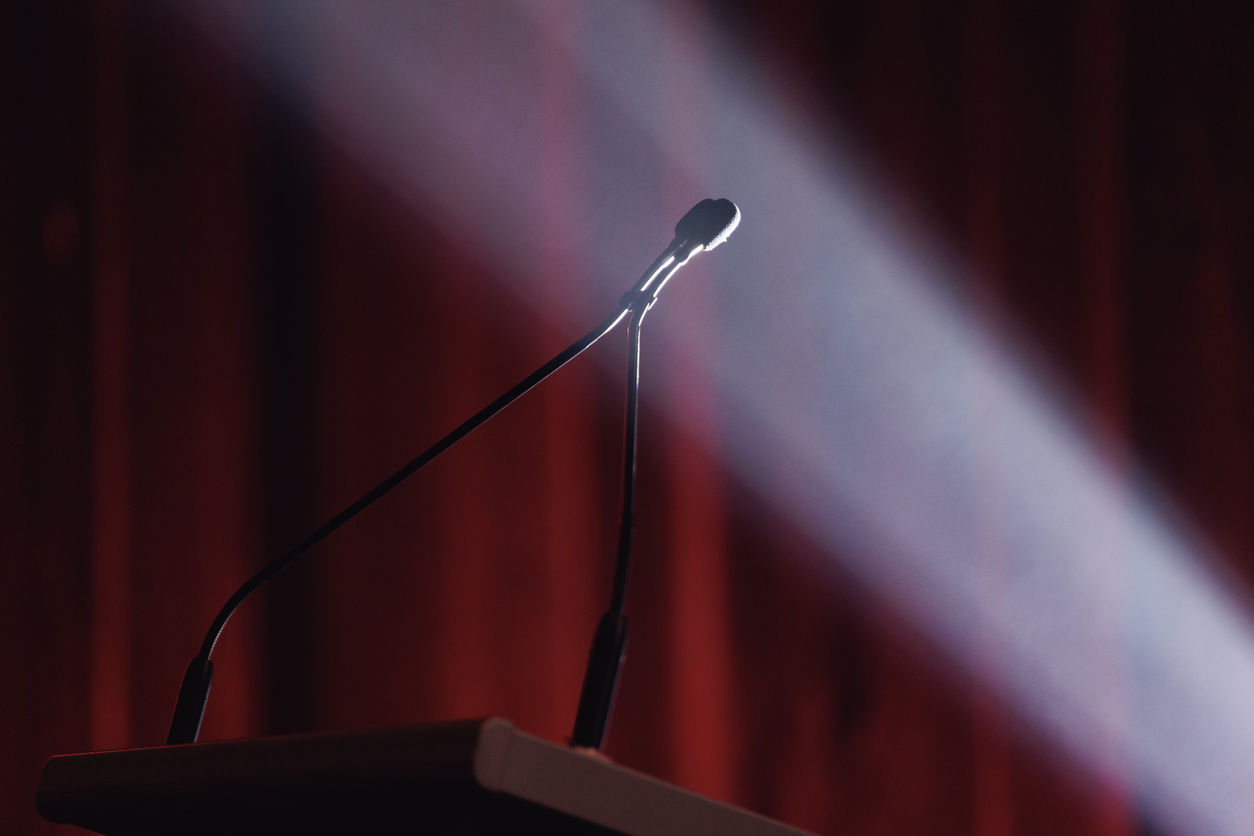 Microphone lit by dramatic stage. lighting Give it your all when speechwriting.