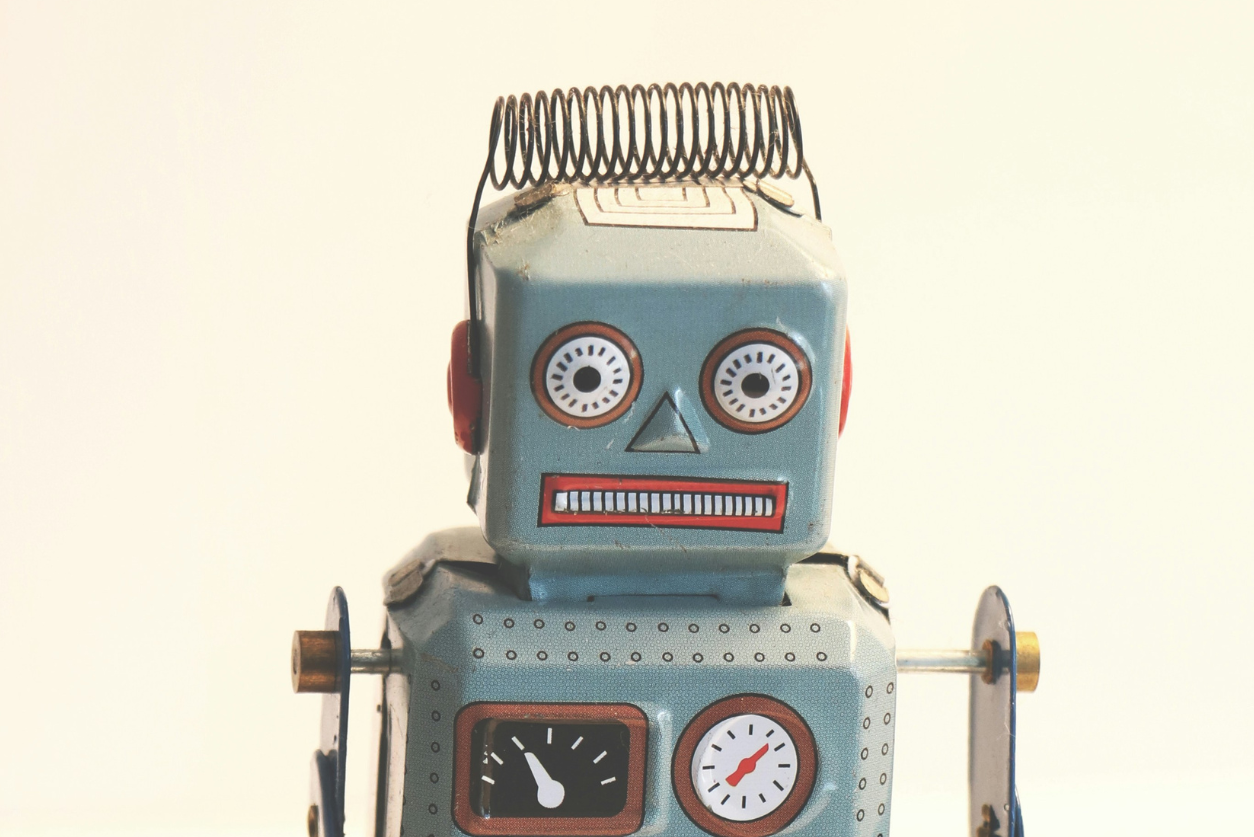 An image of a toy robot on a beige background, accompanying an article about editing ai-generated copy