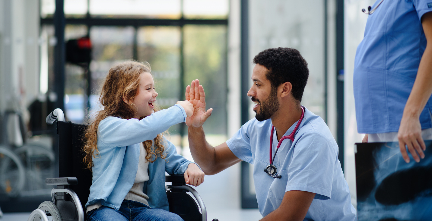 Young multiracial doctor playing with little girl on a wheelchair. (How PR skills can enhance healthcare experience for patients)