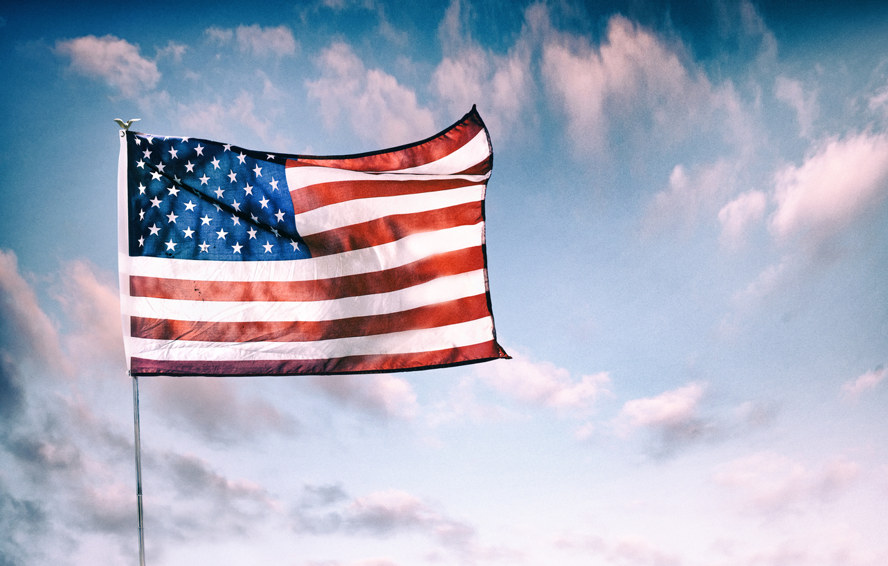 Waving American flag over dramatic sky. (The Scoop: Harris looks to fire up base heading into first debate )